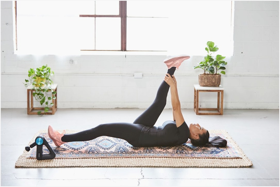 woman in black tank top and black leggings lying on black and white floral area rug