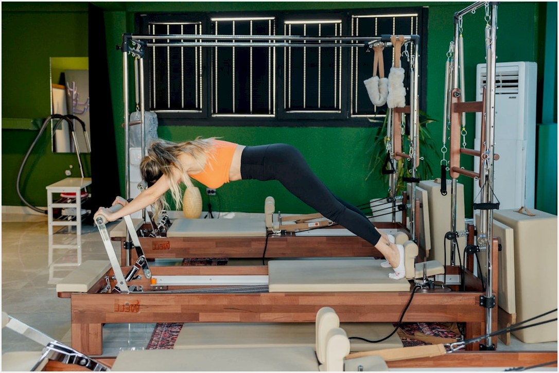 Woman does pilates on a reformer machine.