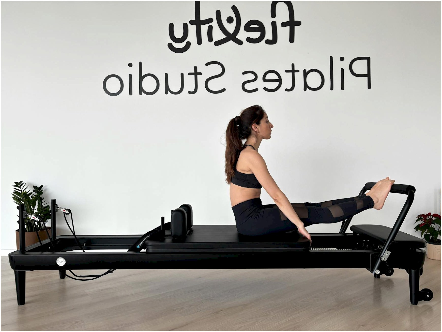Adult woman performing Pilates exercise on reformer at Flexity Pilates Studio.