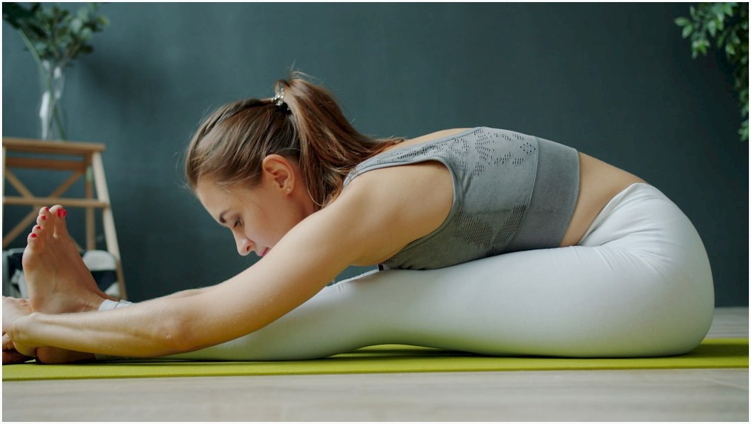 Woman stretching on a yoga mat indoors.