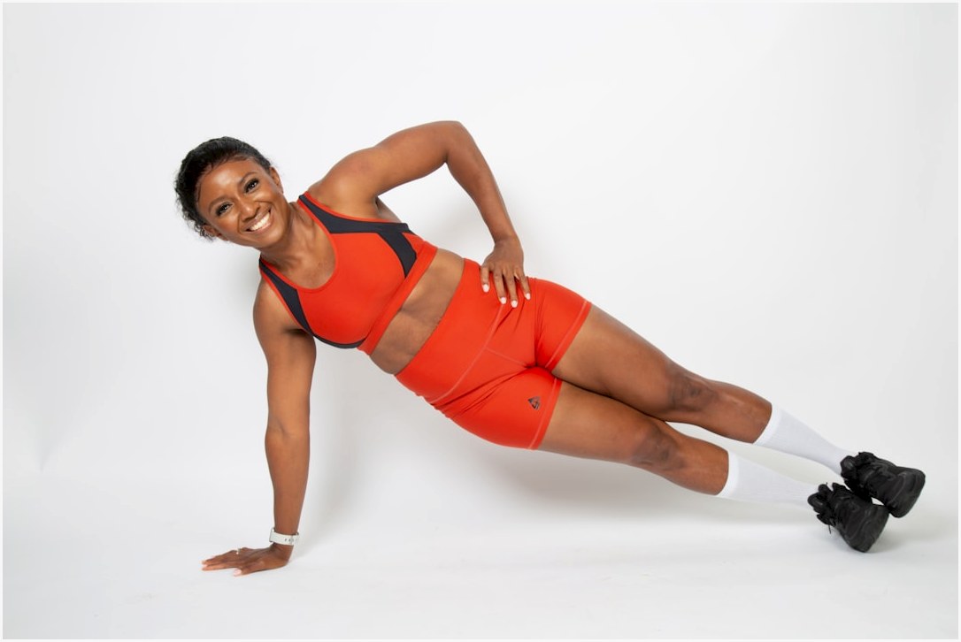 a woman in an orange sports outfit is doing a plank