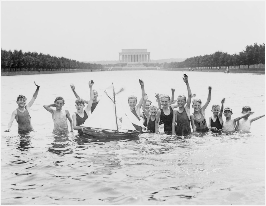 Group of boys waving as they play in the reflecting pool in front of the Lincoln Memorial