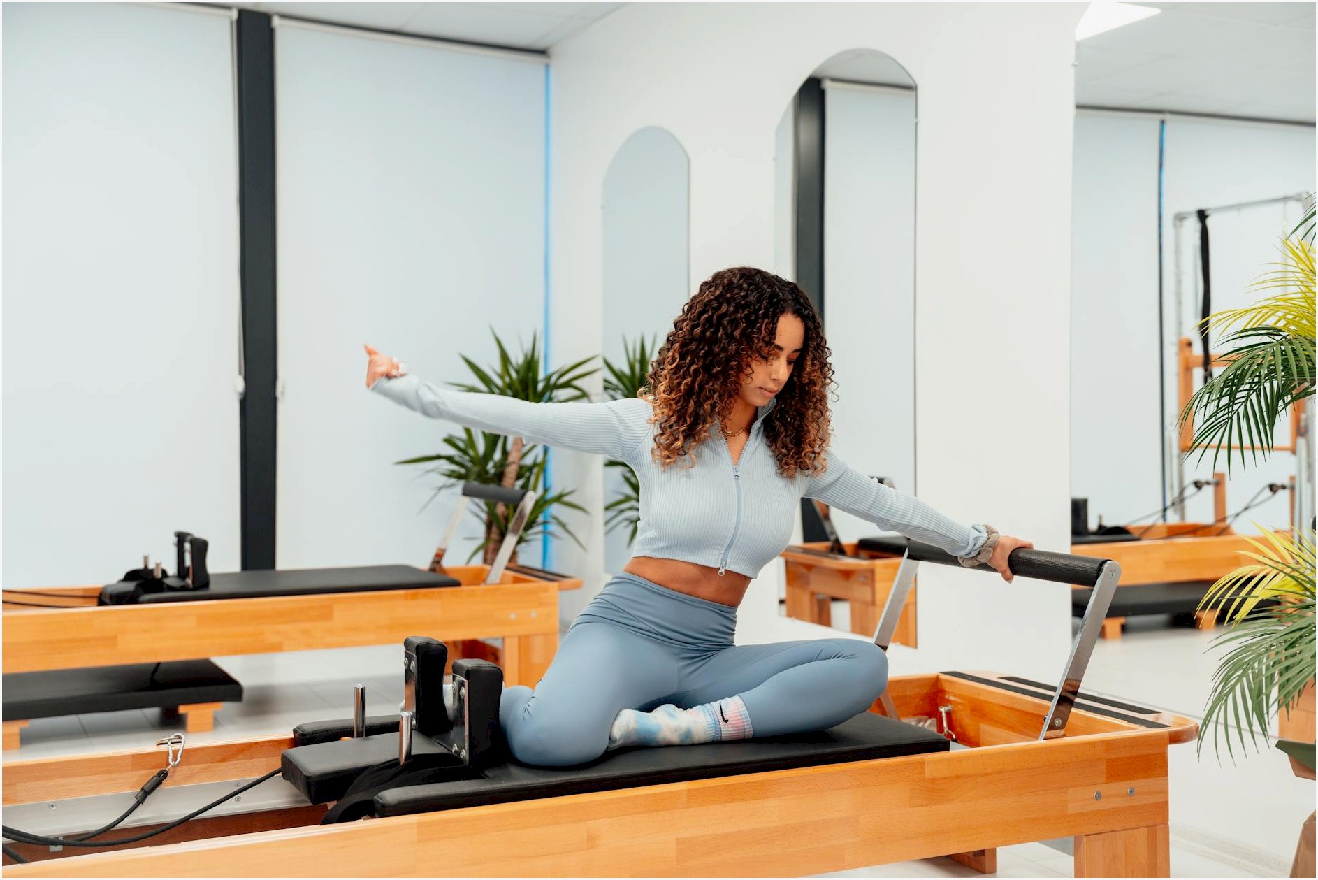 A woman exercising on a reformer in a pilates studio, embodying a healthy lifestyle.