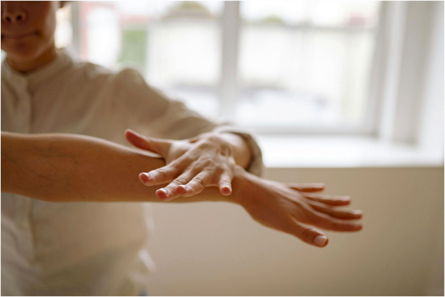 A close-up view of a person using a relaxation technique with hands in motion, in a bright, airy space.