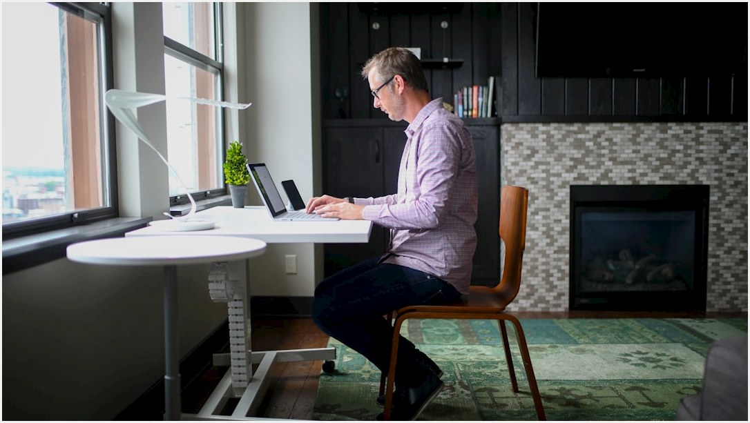 man in gray dress shirt sitting on brown wooden chair using macbook pro
