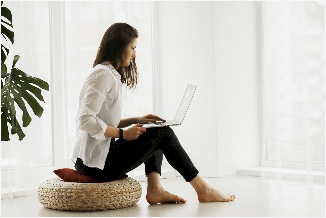 woman in white long sleeve shirt and black pants sitting on brown woven chair