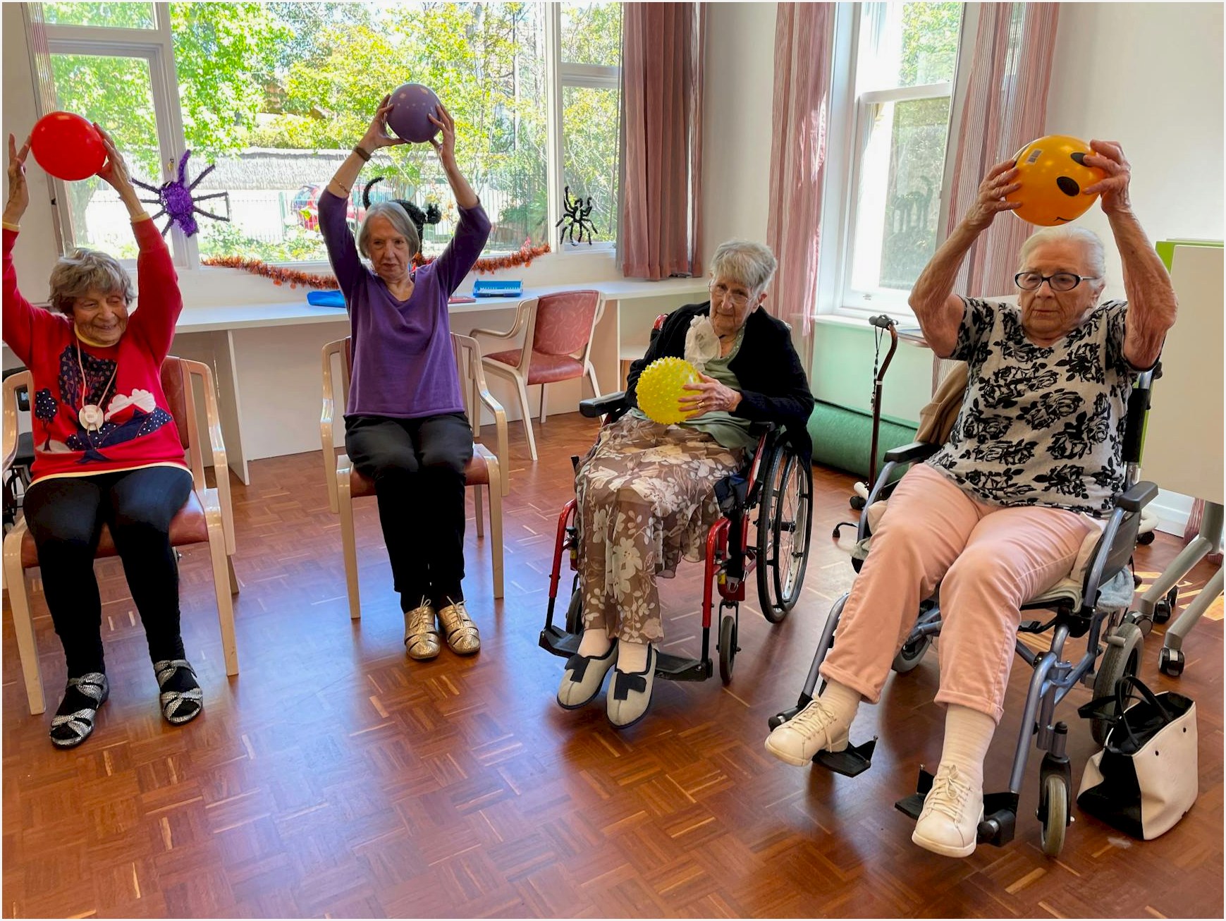 Elderly women engaging in fitness activities with exercise balls in a community center.