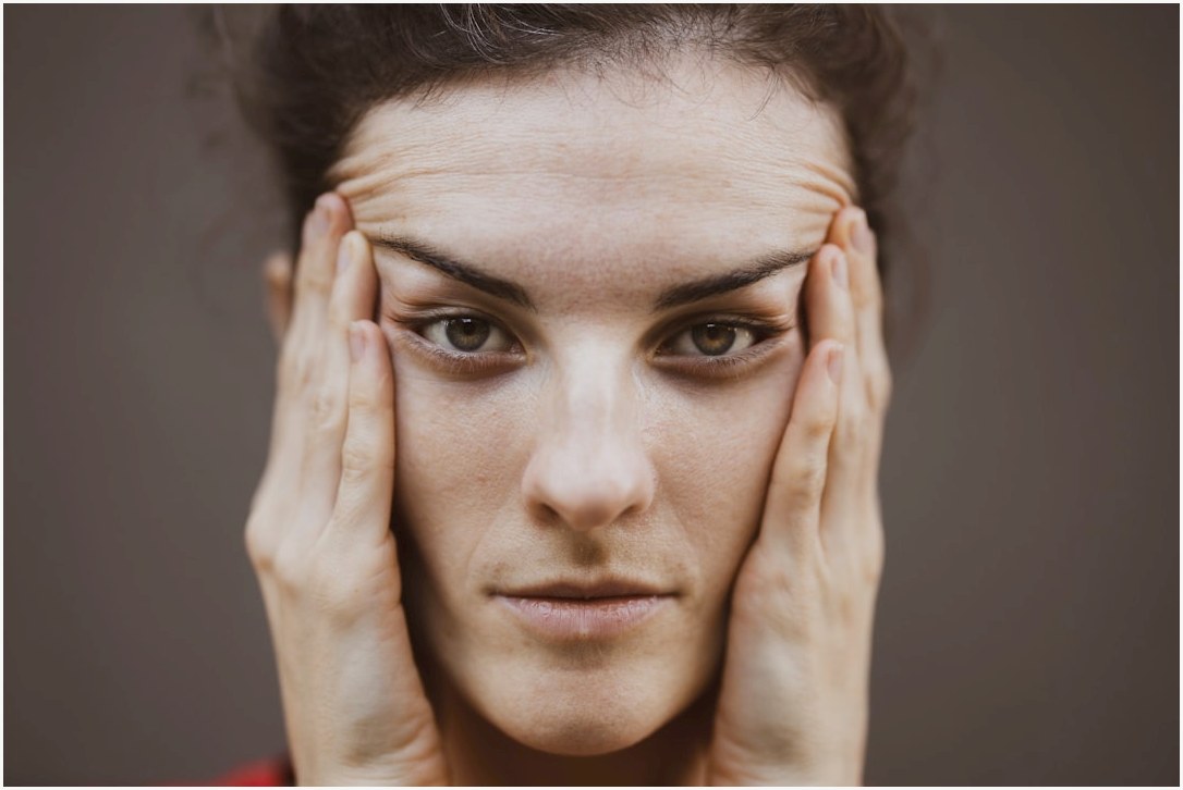 woman in red shirt covering her face with her hand