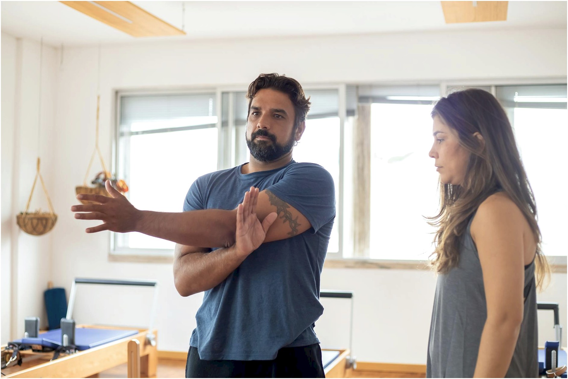 Man and woman during a training session focusing on stretching in a gym.
