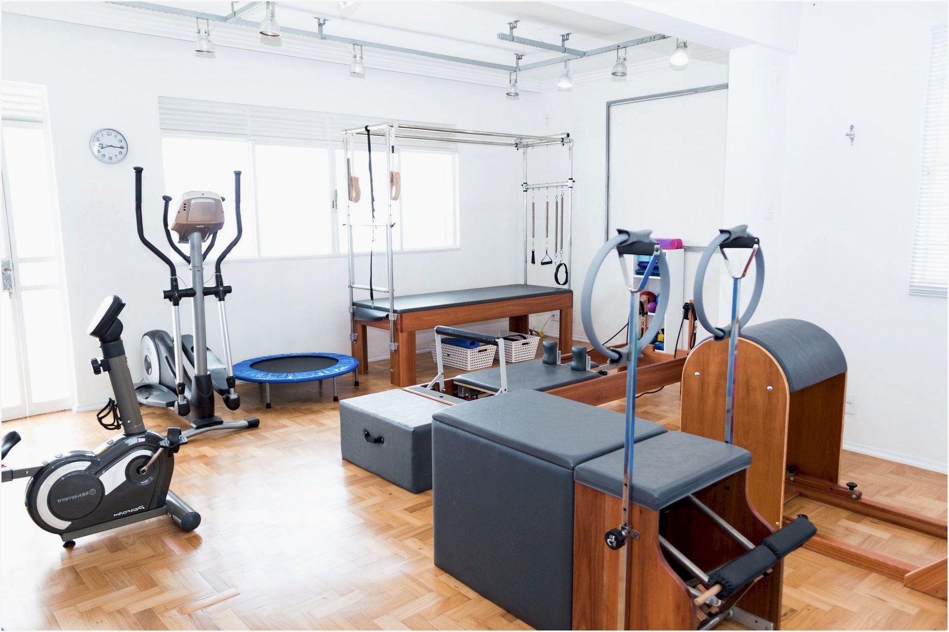 Bright gym space featuring Pilates equipment, exercise bikes, and wooden flooring for a modern workout experience.