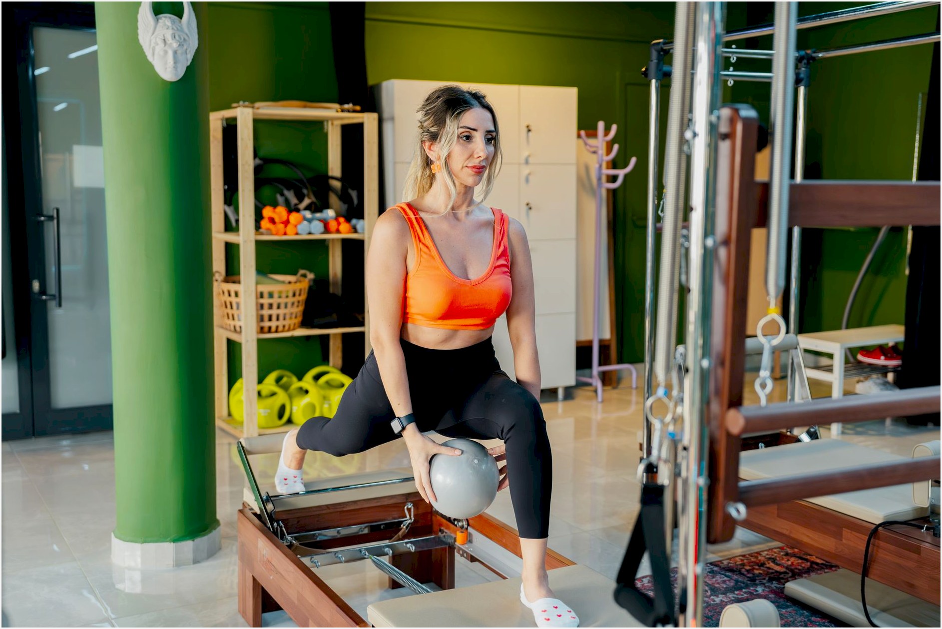 A woman practicing reformer pilates, focusing on balance and strength in a gym studio.