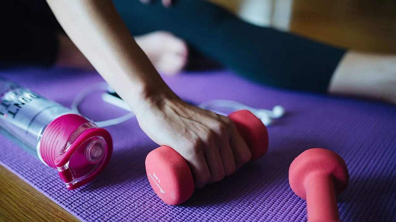 Halteres leves sobre colchonete de Pilates durante treino em casa