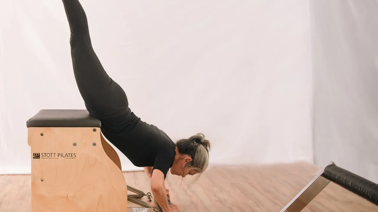 Pessoa praticando Pilates em uma cadeira, com foco no controle do movimento