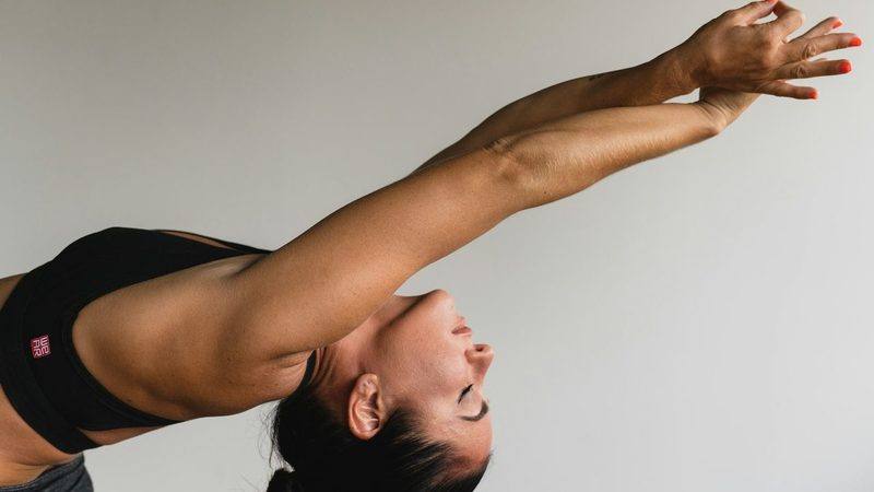 Pessoa praticando um movimento de Pilates com os braços estendidos, em adaptação que exige controle e supervisão