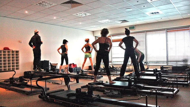 Pessoa praticando Pilates no Reformer em uma sala de exercícios