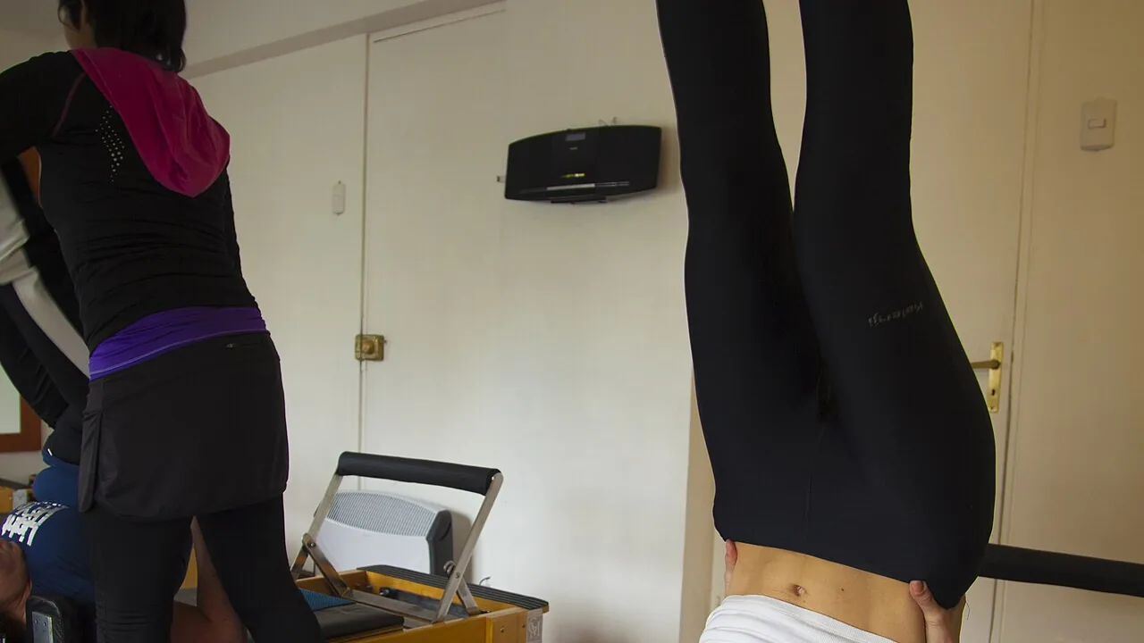 Pessoa praticando Pilates em estúdio com um aparelho Reformer