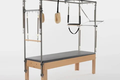 Cadillac ou Trapeze Table de Pilates com estrutura vertical, barras, alças e molas.