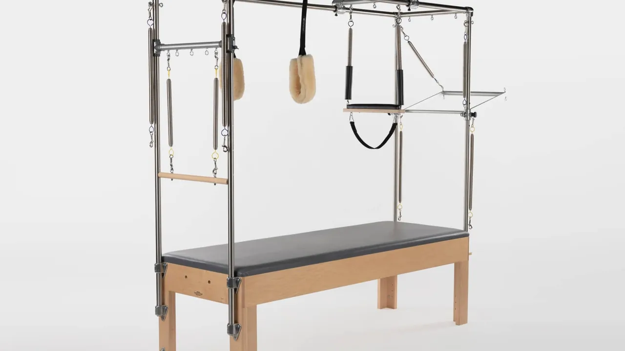 Cadillac ou Trapeze Table de Pilates com estrutura vertical, barras, alças e molas.