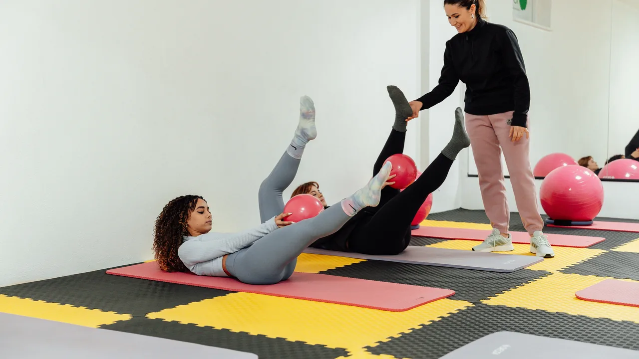 Aula de Pilates no solo com alunas, bolas e instrutora