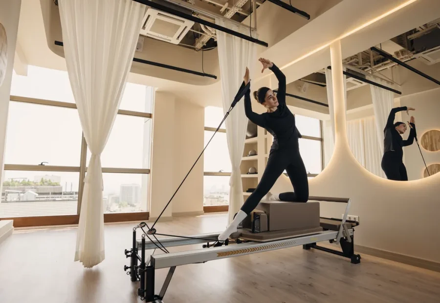 Pessoa praticando Pilates no Reformer em um estúdio iluminado.