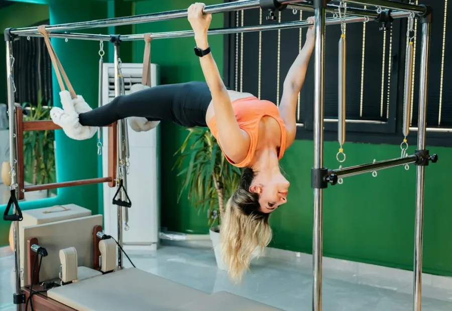 Pessoa praticando Pilates no Cadillac, em uma posição que exige controle dos braços