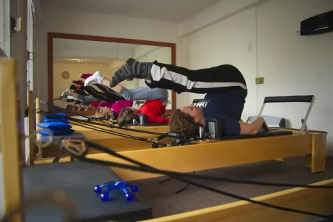 Aula de Pilates em Reformer com praticantes trabalhando controle e amplitude de movimento.
