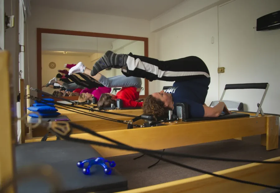 Aula de Pilates em Reformer com praticantes trabalhando controle e amplitude de movimento.