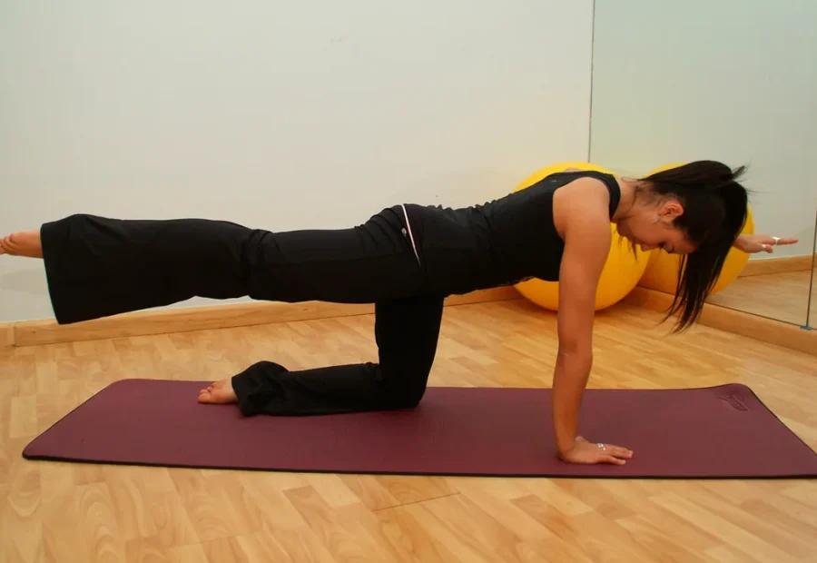 Pessoa praticando Pilates no colchonete em apoio de quatro pontos