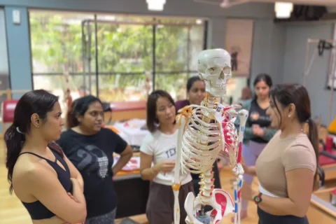 Aula de Pilates com instrutora e modelo anatômico em um estúdio