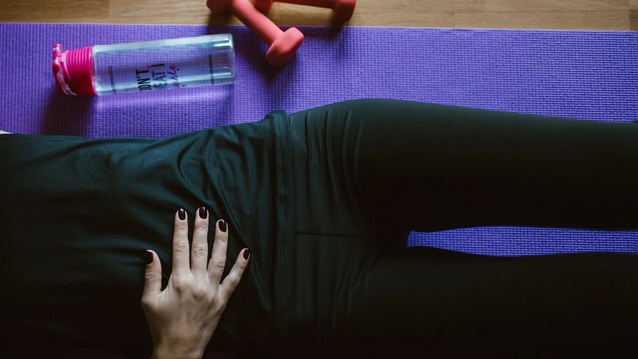 Pessoa deitada sobre colchonete de exercício em uma prática no solo