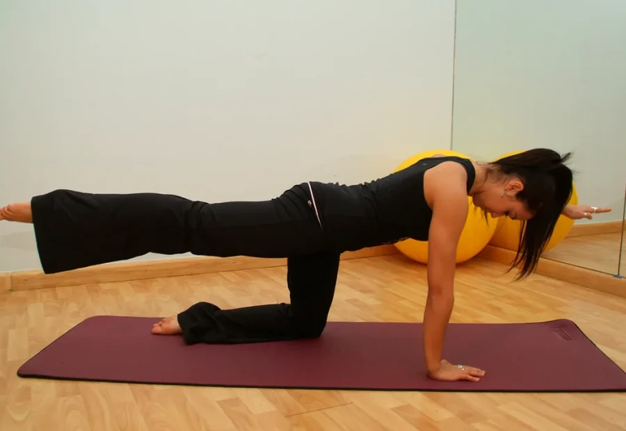 Pessoa praticando Pilates no solo, em posição de quatro apoios, em um estúdio.