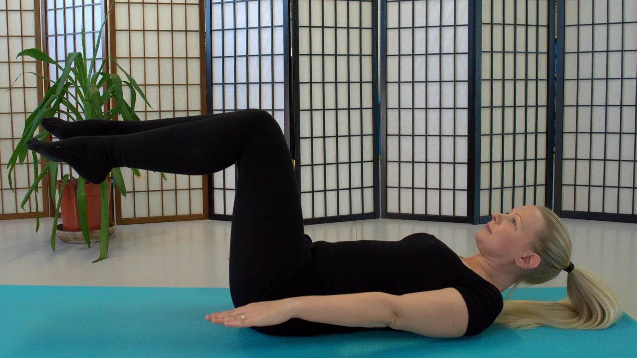 Pessoa praticando Pilates deitada no colchonete, sem apoio das mãos