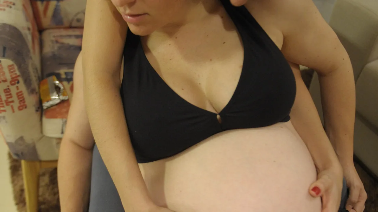 Gestante recebe orientação de uma doula durante exercício com bola