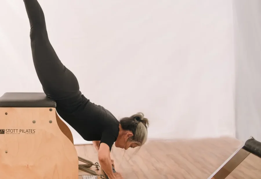 Aparelho de Pilates em uma aula prática, com uma pessoa executando um movimento na cadeira
