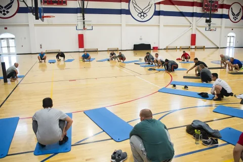 Grupo em aula de técnica de corrida realizando agachamento com orientação
