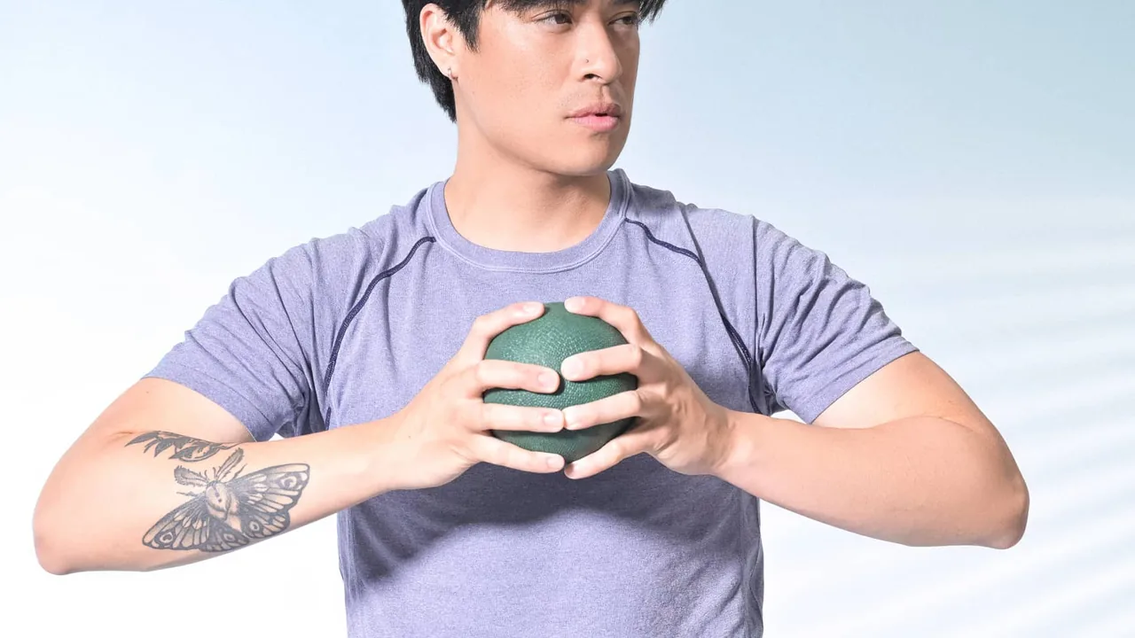 Pessoa segurando uma bola pequena de Pilates durante um exercício