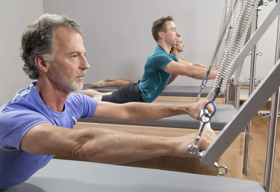Pessoas praticando Pilates em Reformers com torre e molas