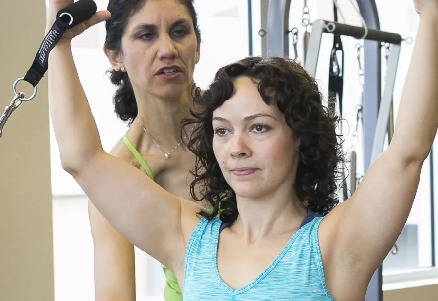 Instrutora orienta aluna durante exercício de Pilates em aparelho