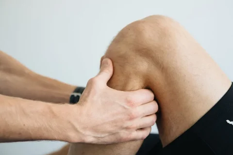 Fisioterapeuta avalia o joelho de uma pessoa durante uma sessão de reabilitação