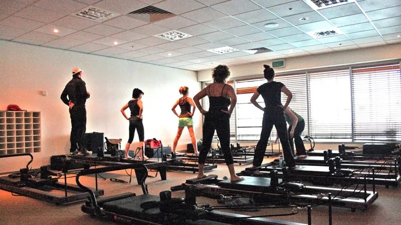 Aula de Pilates em estúdio com pessoas usando aparelhos Reformer