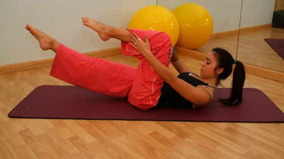 Pessoa praticando Pilates no solo em um estúdio