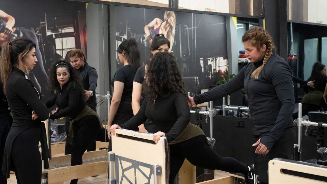 Instrutora orienta alunas em uma aula de Pilates com aparelhos