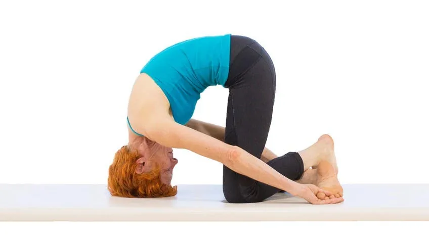 Exercício Crab no Pilates com a pessoa enrolada e a cabeça apoiada no colchonete