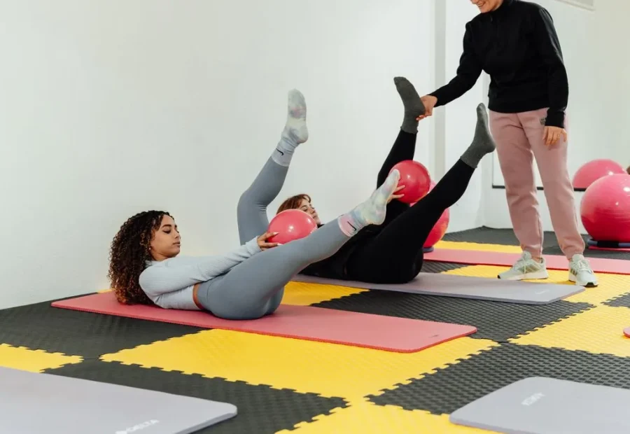 Aula de Pilates no solo com alunos executando exercícios com bolas sob supervisão