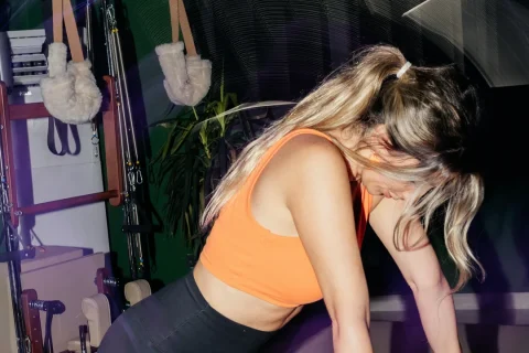 Pessoa em posição de apoio sobre um aparelho Reformer em um estúdio de Pilates