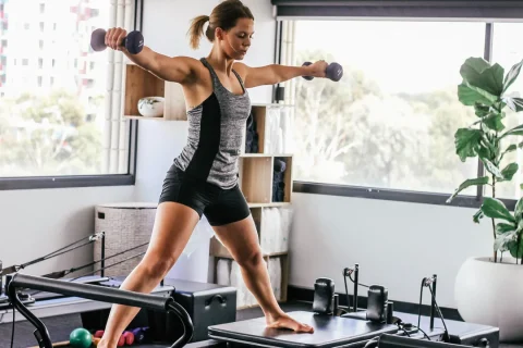 Mulher praticando Pilates no Reformer em um estúdio