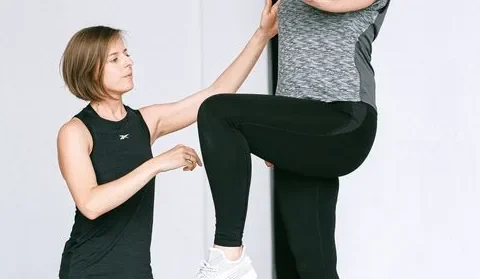Instrutora acompanha uma mulher idosa durante um exercício