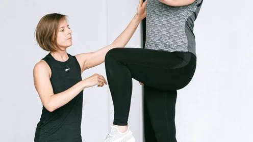 Instrutora acompanha uma mulher idosa durante um exercício