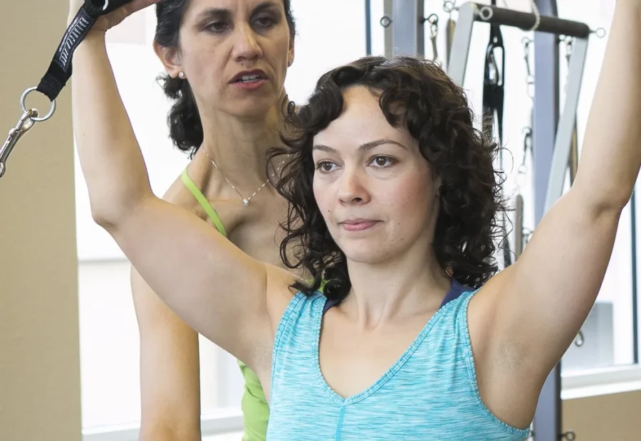 Instrutora orientando uma aluna em um exercício de Pilates no aparelho
