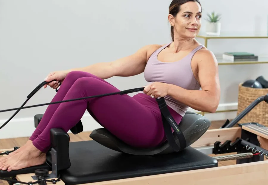 Pessoa sentada sobre o Oov em um Reformer de Pilates